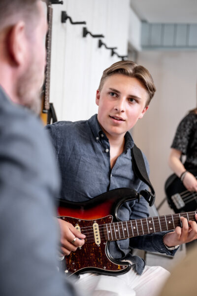 Musikelev spelar gitarr och skriver låt.